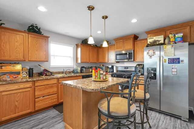 5617 Branchville Dr, Canal Winchester, OH 43110 - kitchen featuring stainless steel appliances, light wood-style flooring, a sink, a center island, and a kitchen bar