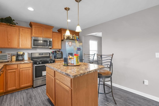 5617 Branchville Dr, Canal Winchester, OH 43110 - kitchen with stainless steel appliances, a center island, dark wood-style floors, a breakfast bar area, and baseboards