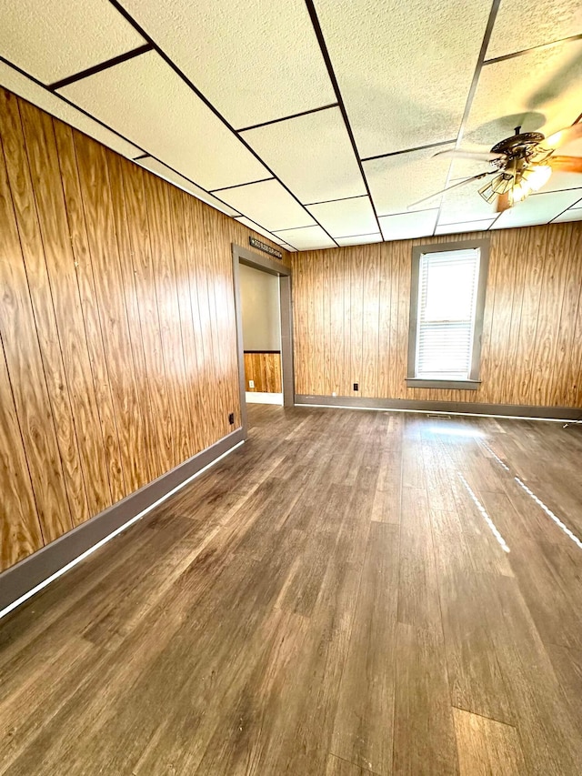 619 Sugar St, Marion, OH 43302 - unfurnished living room featuring wood finished floors, a drop ceiling, a ceiling fan, and wooden walls