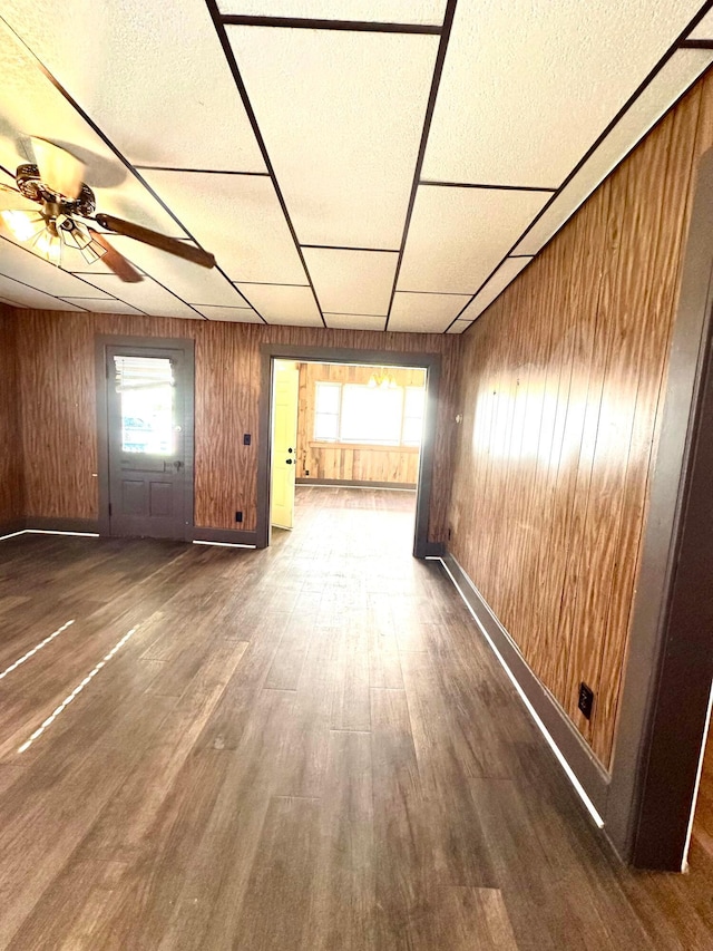 619 Sugar St, Marion, OH 43302 - unfurnished living room featuring wood walls, a ceiling fan, wood finished floors, a paneled ceiling, and baseboards