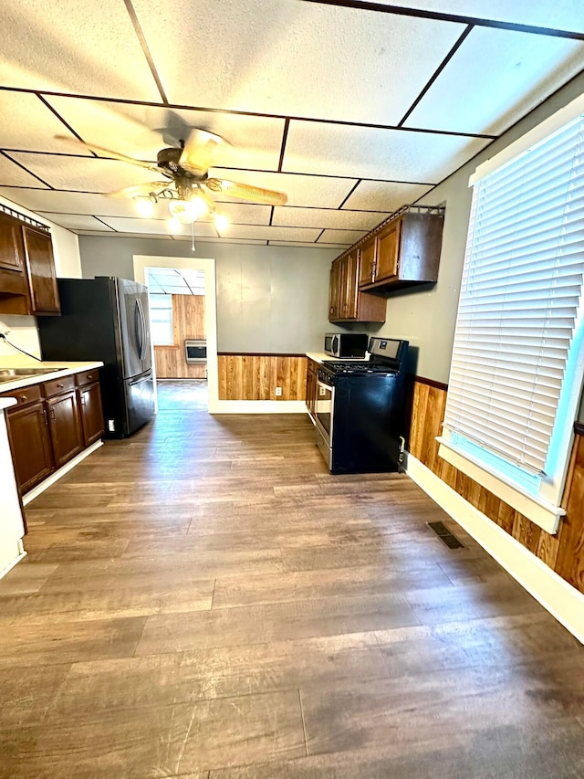 619 Sugar St, Marion, OH 43302 - kitchen featuring stainless steel appliances, ceiling fan, wood finished floors, wainscoting, and wood walls