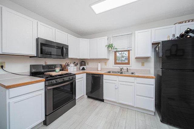 5039 Lee Rd, South Bloomfield, OH 43103 - kitchen with black appliances, a sink, light countertops, white cabinetry, and light wood-style floors
