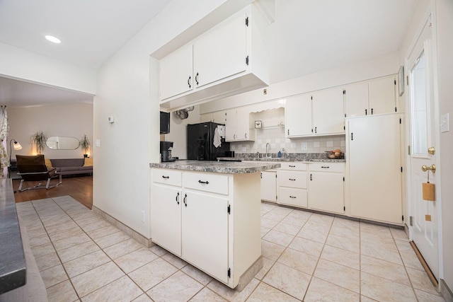 kitchen featuring freestanding refrigerator, light tile patterned floors, a peninsula, decorative backsplash, and recessed lighting