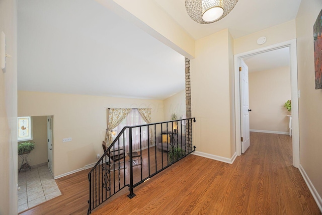 corridor featuring an upstairs landing, wood finished floors, and baseboards