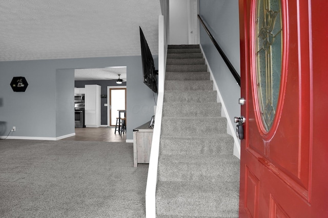 staircase with baseboards, carpet, a textured ceiling, and ceiling fan
