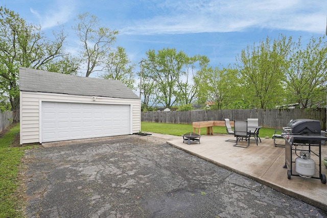 view of patio featuring a fire pit, an outbuilding, and a detached garage