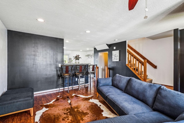 living room with a dry bar, stairs, wood finished floors, recessed lighting, and a textured ceiling