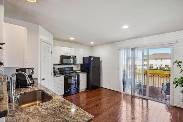 kitchen with black appliances, a sink, light stone countertops, dark wood-style flooring, and white cabinetry
