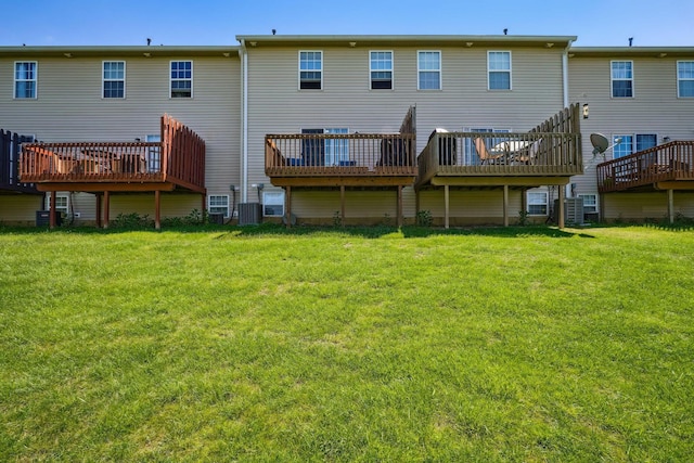 rear view of house featuring cooling unit, a lawn, and a deck