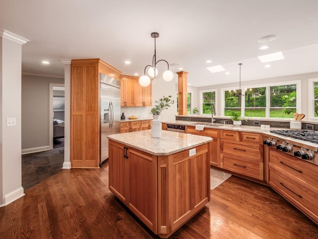kitchen with appliances with stainless steel finishes, a sink, a skylight, decorative backsplash, and a center island
