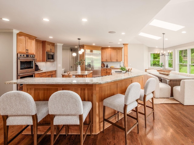 kitchen featuring built in appliances, a sink, a skylight, decorative backsplash, and wood finished floors