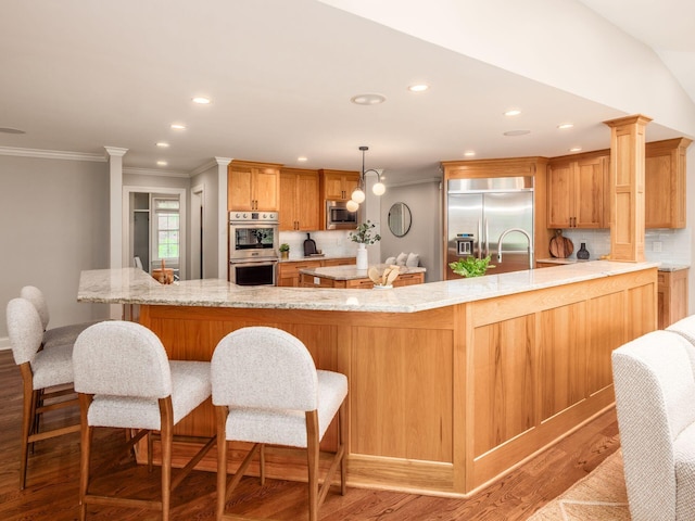 kitchen featuring built in appliances, light wood-style floors, crown molding, decorative backsplash, and a peninsula