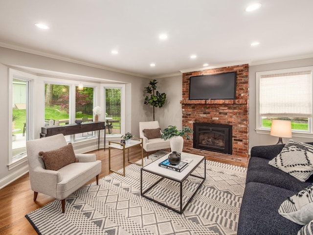living room with light wood-style floors, a brick fireplace, recessed lighting, ornamental molding, and baseboards