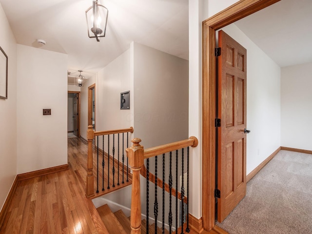 corridor featuring an upstairs landing, baseboards, and wood finished floors