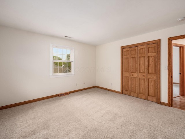 unfurnished bedroom with carpet floors, baseboards, and a closet