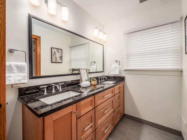 bathroom with double vanity and baseboards