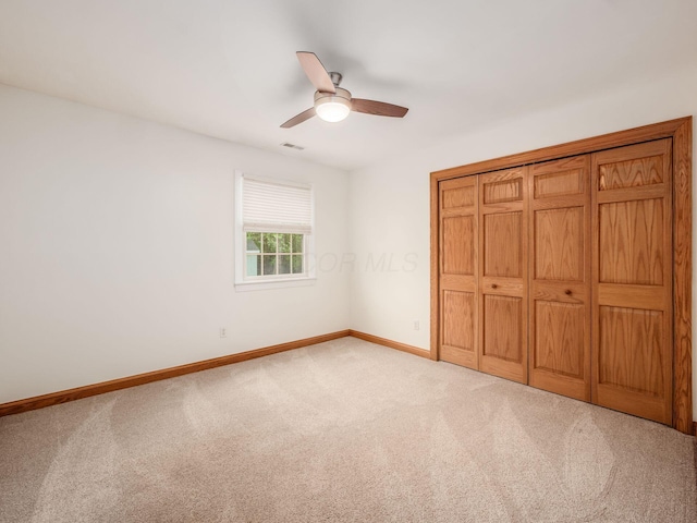 unfurnished bedroom with carpet floors, baseboards, ceiling fan, and a closet