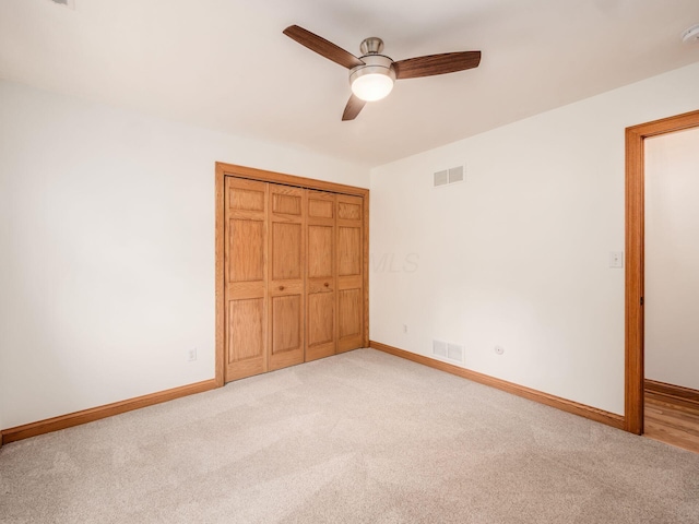 unfurnished bedroom featuring baseboards, light carpet, a closet, and a ceiling fan