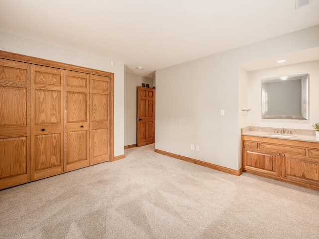unfurnished bedroom with light carpet, baseboards, a sink, and ensuite bath