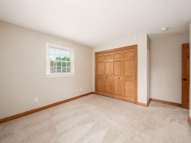 unfurnished bedroom with light colored carpet, baseboards, and a closet