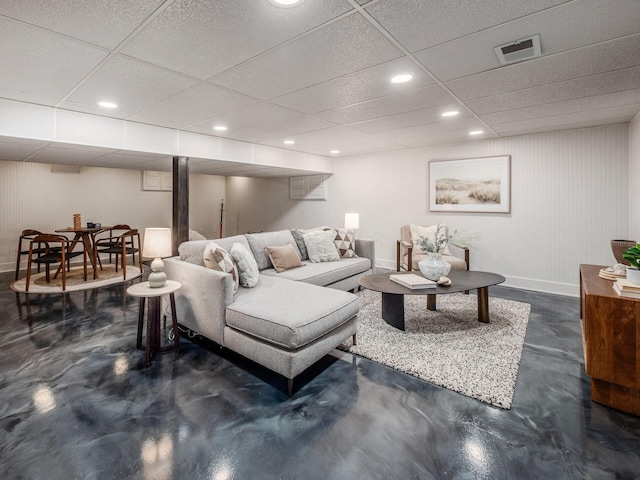 living room featuring finished concrete flooring, baseboards, recessed lighting, and a paneled ceiling