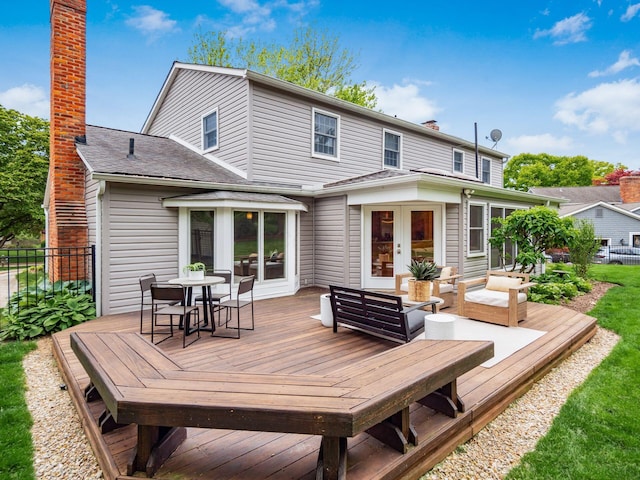 back of house with a chimney, a deck, outdoor dining area, and fence
