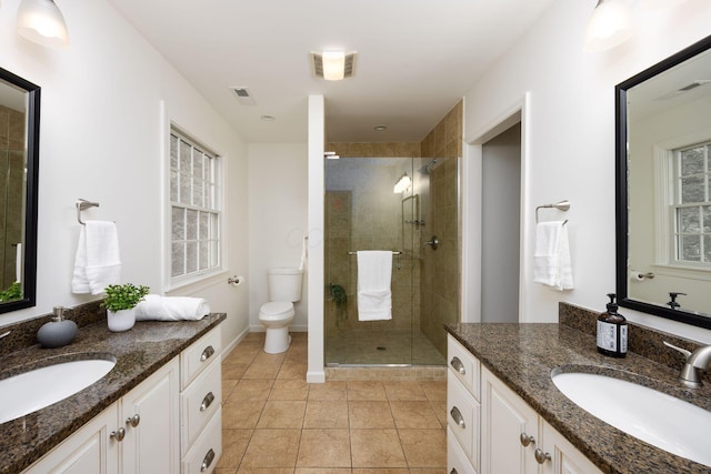 full bath featuring a stall shower, toilet, two vanities, and tile patterned flooring