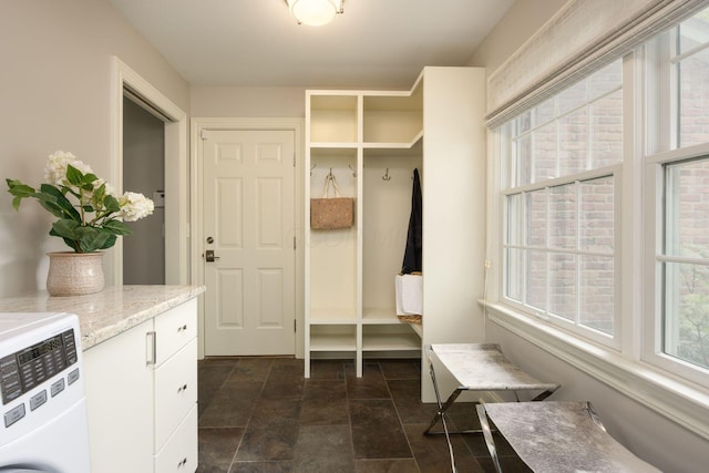 mudroom with plenty of natural light, dark stone finish floors, and washer / dryer