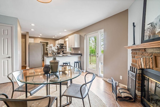 8950 Woodhaven Rd, Johnstown, OH 43031 - dining space featuring a glass covered fireplace, light wood-style flooring, baseboards, and recessed lighting