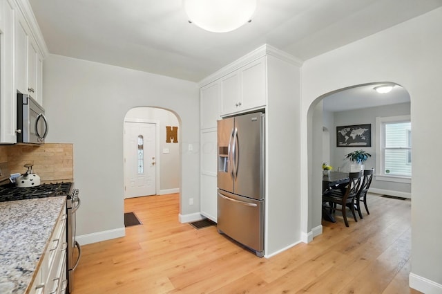 1545 Westwood Ave, Columbus, OH 43212 - kitchen with appliances with stainless steel finishes, arched walkways, light wood finished floors, and white cabinets