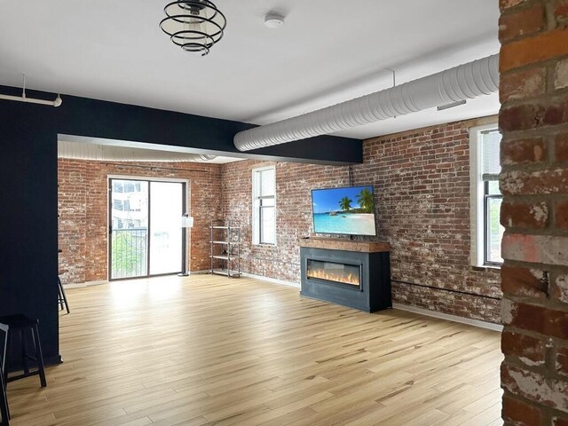 432 E Rich St Unit 3K, Columbus, OH 43215 - unfurnished living room featuring brick wall, a glass covered fireplace, wood finished floors, and baseboards