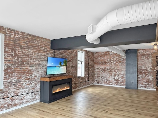 432 E Rich St Unit 3K, Columbus, OH 43215 - unfurnished living room featuring brick wall, a glass covered fireplace, baseboards, and wood finished floors