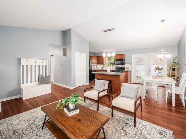 living room with a chandelier, lofted ceiling, dark wood finished floors, and baseboards
