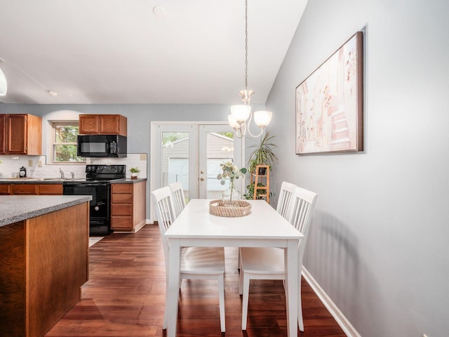 dining area featuring dark wood finished floors, a chandelier, and vaulted ceiling