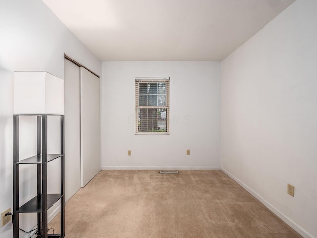 spare room with light carpet and baseboards