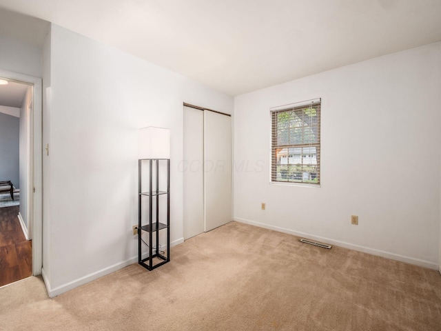 unfurnished bedroom featuring carpet, baseboards, and a closet