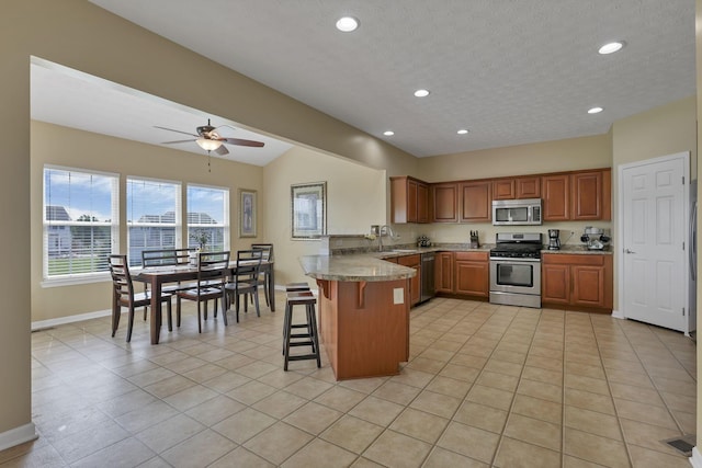 135 Tassel View St, Pataskala, OH 43062 - kitchen featuring appliances with stainless steel finishes, a peninsula, baseboards, a kitchen breakfast bar, and a sink