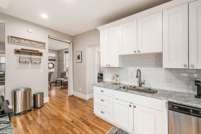1105 Say Ave, Columbus, OH 43201 - kitchen featuring stainless steel dishwasher, a sink, tasteful backsplash, light wood-style floors, and white cabinetry