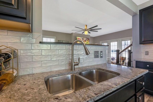 5119 Butterworth Green Dr, New Albany, OH 43054 - kitchen featuring a sink, light stone counters, backsplash, a ceiling fan, and dark cabinetry