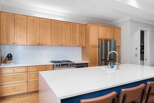 308 Jackson St, Columbus, OH 43206 - kitchen with appliances with stainless steel finishes, crown molding, a sink, an island with sink, and a breakfast bar
