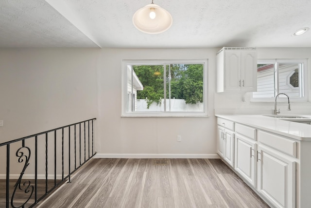 3368 Pine Valley Rd, Columbus, OH 43219 - kitchen with a sink, light wood-type flooring, white cabinets, light countertops, and a textured ceiling