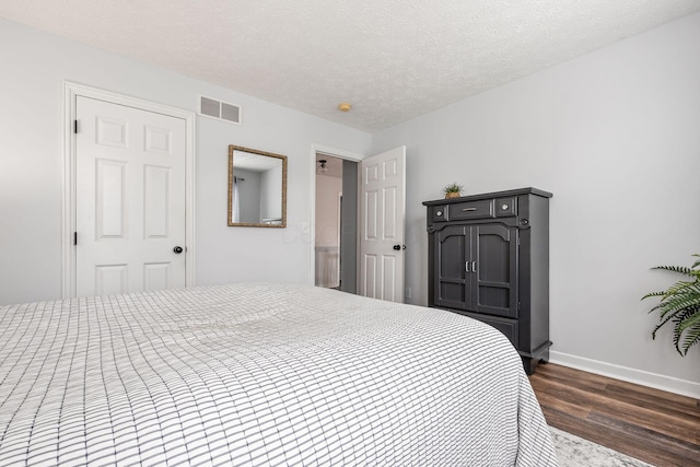 bedroom featuring dark wood-style flooring, baseboards, and a textured ceiling