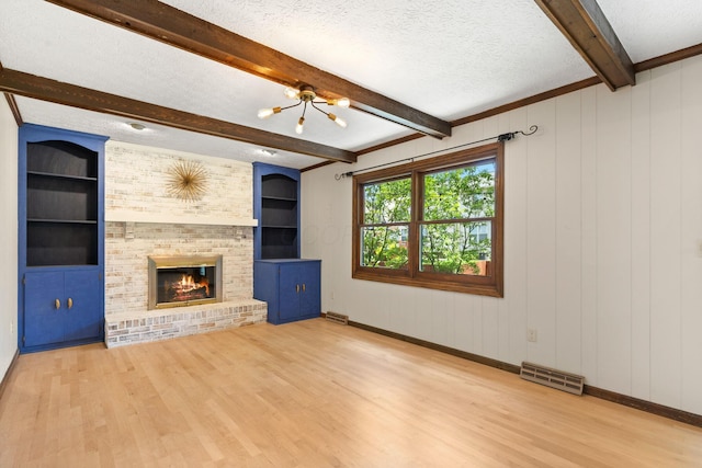 750 Pepper Ct, Westerville, OH 43082 - unfurnished living room featuring wood finished floors, a chandelier, a textured ceiling, a brick fireplace, and beam ceiling