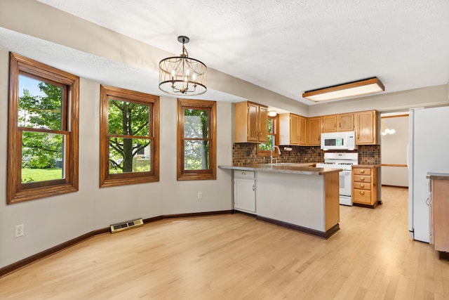 750 Pepper Ct, Westerville, OH 43082 - kitchen with white appliances, a peninsula, light wood-type flooring, backsplash, and a chandelier