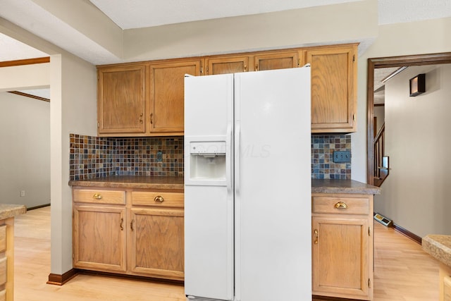 750 Pepper Ct, Westerville, OH 43082 - kitchen with white fridge with ice dispenser, backsplash, dark countertops, and light wood-style flooring