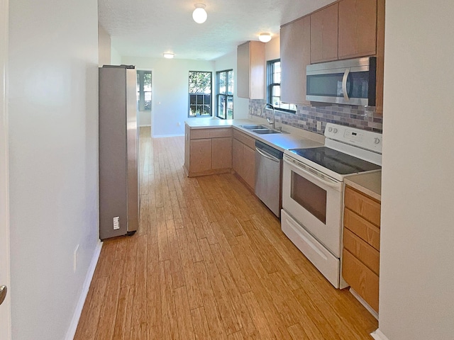 3118 Legion Ln, Columbus, OH 43232 - kitchen featuring appliances with stainless steel finishes, light wood-style flooring, backsplash, a sink, and baseboards