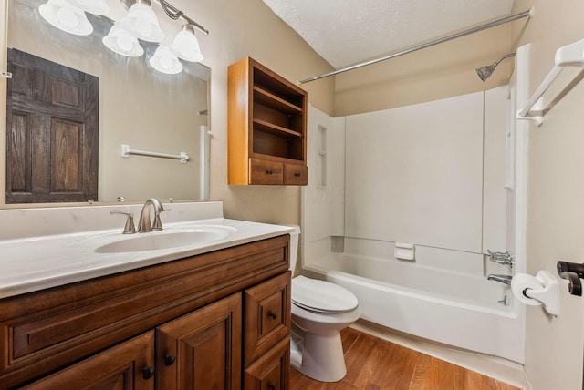 full bath with toilet,  shower combination, wood finished floors, vanity, and a textured ceiling
