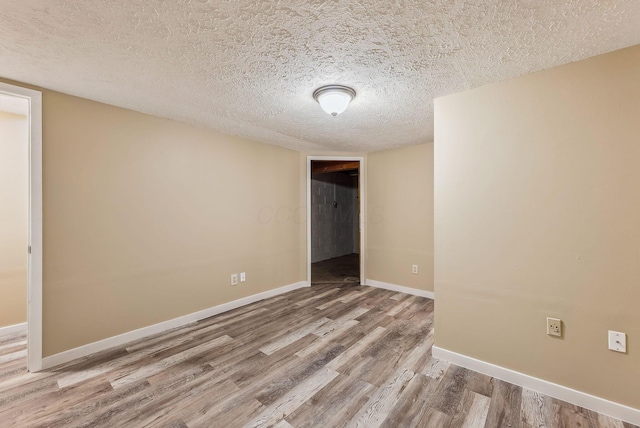 unfurnished bedroom with wood finished floors, a textured ceiling, and baseboards