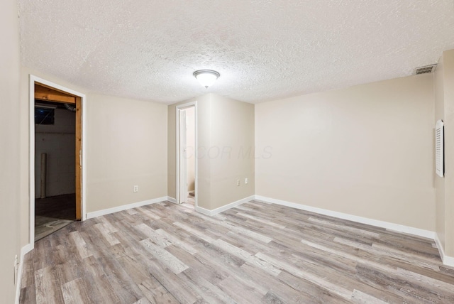 basement with light wood-style flooring, baseboards, and a textured ceiling