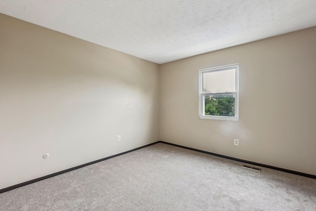 empty room with carpet, baseboards, and a textured ceiling